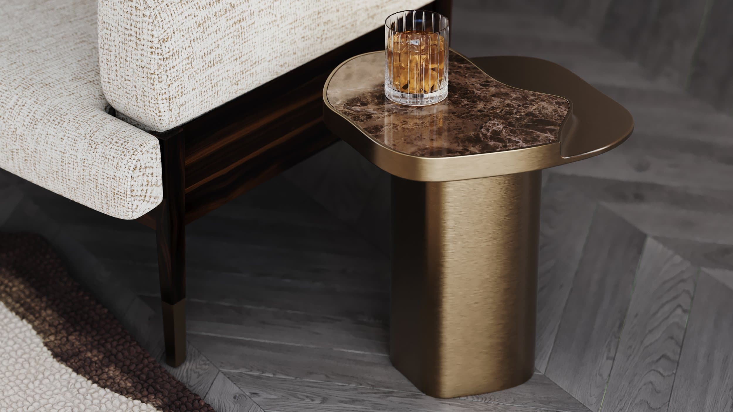 Brushed brass and brown marble side table beside a bouclé sofa — material and finish detail